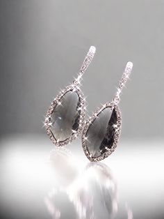 the pair of earrings is made from silver and black stones with diamonds on them,