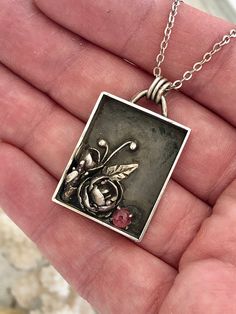 The sweetest cast succulents that resemble roses are framed in a shadow box with a pink tourmaline. A peaceful silver dove takes flight on the back.  Fine and sterling silver with an 18 inch silver chain Made in the Spruce Mountain Studio at 9,300ft, by Juliann Free shipping Follow me on Instagram at SpruceMountain_Studio Shadow Box Jewelry, Silversmithing Jewelry, The Spruce, Metal Clay Jewelry, Accessories Bags Shoes, Owl Necklace, Box Jewelry, Artistic Jewelry, Sterling Silver Necklace