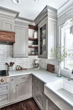 a kitchen with gray cabinets and white counter tops is pictured in this image, there are plants on the window sill