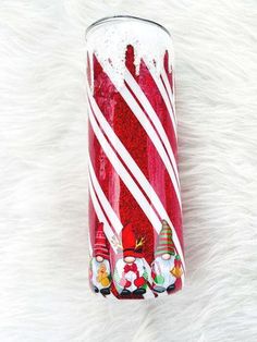 a red glass filled with candy canes on top of white fur