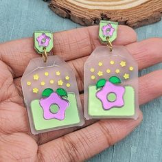 Starfruit tea bag statement earrings. A tea bag with a purple stardrop and green accents. They are made with frosted and shiny acrylics for a dreamy aesthetic. Order with the Default Stud to get the earring as pictured with tag topper. If you would prefer an ear hook, huggie/leverback, or clip-on the pentagon tag shape on top will be replaced. Metal is silver-toned, if you would like gold-toned metal, add it to the special instructions in your cart!Dimensions:1.5 in (38mm) L X 1.1 in (27mm) W2.0 Green Tea Earrings, Silly Earrings, Dreamy Aesthetic, Laser Engraved Ideas, Music Coloring, Acrylic Jewellery, Dream Nails, Green Accents, Ear Hook