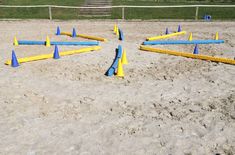 several blue and yellow cones are arranged in the middle of a sandy area with grass