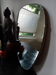 a mirror sitting on top of a table next to a vase