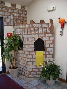 there is a fake castle made out of bricks on the wall next to potted plants