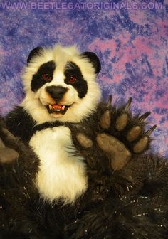 a stuffed panda bear sitting on top of a purple and black background with his paws up