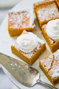 several pieces of cake on a white plate with a silver serving spoon and whipped cream