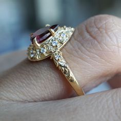 a close up of a person's hand holding a ring with a stone in it