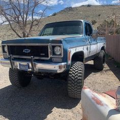 a blue truck parked on top of a dirt road