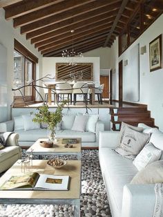 a living room filled with white furniture and lots of wooden beams on top of it