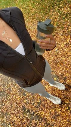 a woman is sitting on the ground with her legs crossed and holding a coffee cup