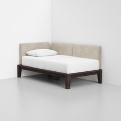 a white bed with two pillows on it and a wooden frame in front of the headboard