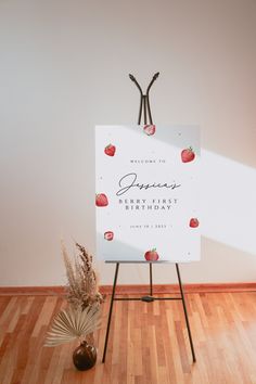 a sign with strawberries on it in front of a vase