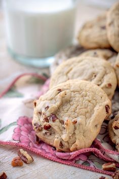 a pile of cookies sitting on top of a pink napkin next to a glass of milk