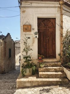 an old building with steps leading up to the door and potted plants on either side