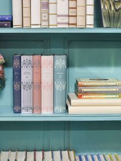 several books are sitting on the shelves next to each other in front of a vase with flowers