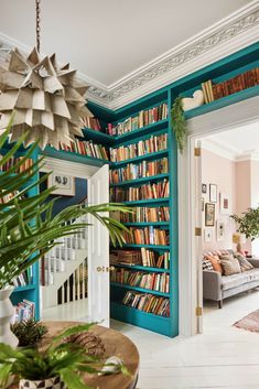 a living room filled with lots of books on top of a blue book shelf next to a doorway