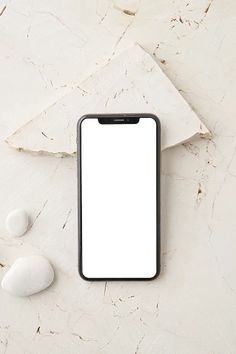 an iphone sitting on top of a white table next to rocks and a paper towel