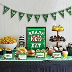 a football themed party with snacks and desserts on a green tableclothed table