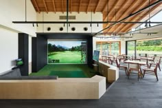 an indoor golf course with tables and chairs