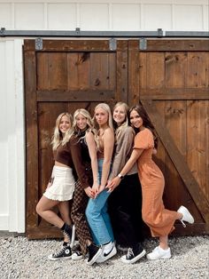 a group of young women standing next to each other in front of a wooden door