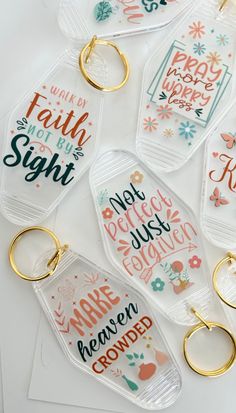 six clear keychains with different sayings on them, one is gold and the other is white