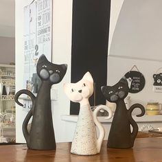 three black and white cat figurines sitting on top of a wooden table