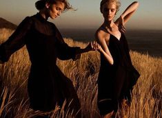 two women in black dresses walking through tall grass