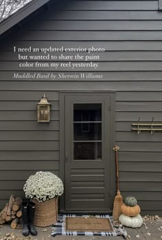 a gray house with a black and white checkered rug on the front porch next to it