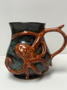 a black and brown cup with an octopus on the inside is sitting on a white surface