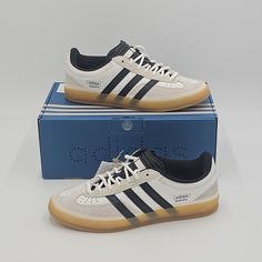 Introducing the adidas Bad Bunny x Gazelle Indoor sneaker, designed for the ultimate comfort and performance. This limited edition sneaker features a lace-up closure and a low-top shoe shaft style, with a striped pattern and a white and black color scheme. The upper is made of leather and the lining is made of fabric, while the insole is made of foam and the outsole is made of rubber. This sneaker is perfect for a variety of activities, including gym and training, walking, soccer, and running and jogging. It is also suitable for casual wear and workwear, and is ideal for both men and women. The adidas Gazelle has a rich history and this collaboration with Bad Bunny and Benito is a must-have for any sneaker enthusiast. Condition is brand new and unworn. Ships same business day via FedEx. Fe Adidas Bad Bunny, Adidas Gazelle Indoor, Limited Edition Sneakers, Bad Bunny, Adidas Gazelle, White Adidas, Top Shoes, Mens Shoes Sneakers, Adidas Shoes