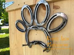 a metal dog's paw is attached to the side of a wooden fence,