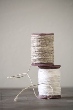 two spools of white and brown twine sitting on top of each other