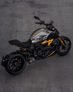 a black and yellow motorcycle is parked on the pavement in an empty parking lot with no one around it