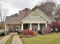 a house that is in the middle of some grass and flowers on the front lawn