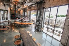 the inside of a restaurant with lots of tables and stools in front of large windows