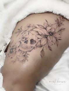 a woman with a skull and flowers tattoo on her thigh