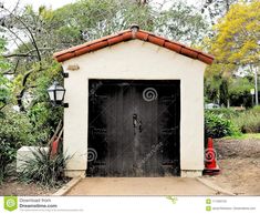 an old garage with a red fire hydrant in the foreground and trees in the background