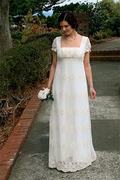 a woman in a long white dress is walking down the street with her bouquet on her hand