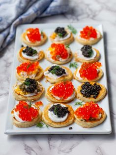 small appetizers with red and black cavias are arranged on a white plate