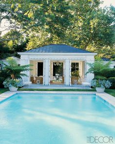 a pool with a gazebo in the middle of it surrounded by greenery and trees