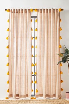 a window with yellow pom - poms hanging from it's curtain rod