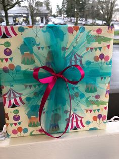 a gift wrapped in blue and pink paper with a bow on it's side