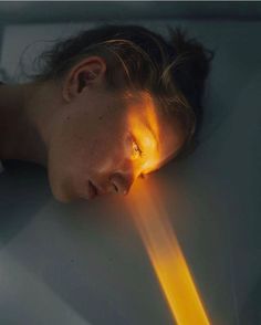 a woman is laying down with her head on the table and light coming from behind her