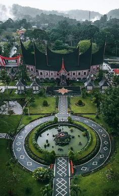 an aerial view of a circular garden in the middle of a lush green area with trees and buildings