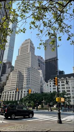 a black car is driving down the street in front of tall buildings and traffic lights