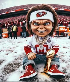 a stuffed doll is sitting on the ground with a trophy in his hand and people behind him