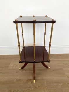 a small wooden table with gold trimmings on the top and two shelves below it