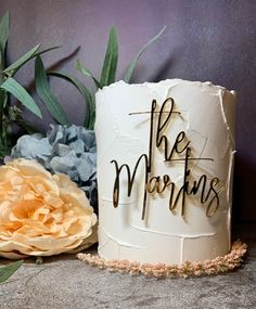 a white cake with the words the morning on it next to some flowers and leaves