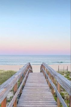 a wooden walkway leading to the beach at sunset with ocean and sky in the background