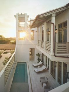 the sun shines brightly in front of a house with an outdoor swimming pool and lounge chairs